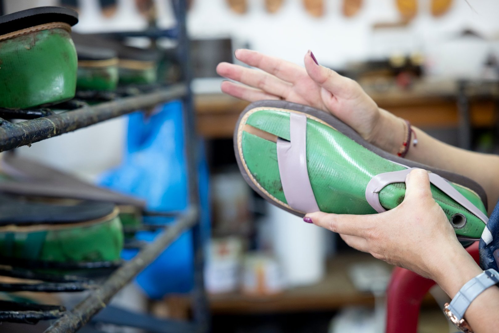 Details from a small shoe atelier of a woman using glue to stick the base shoe.