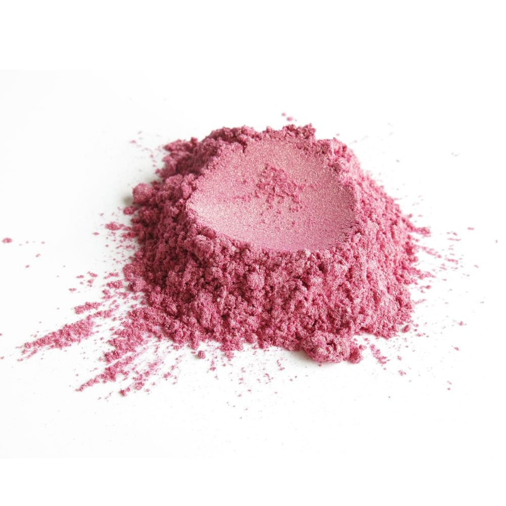 A small pile of pink powder on a white surface, with a smooth texture and fine granules.