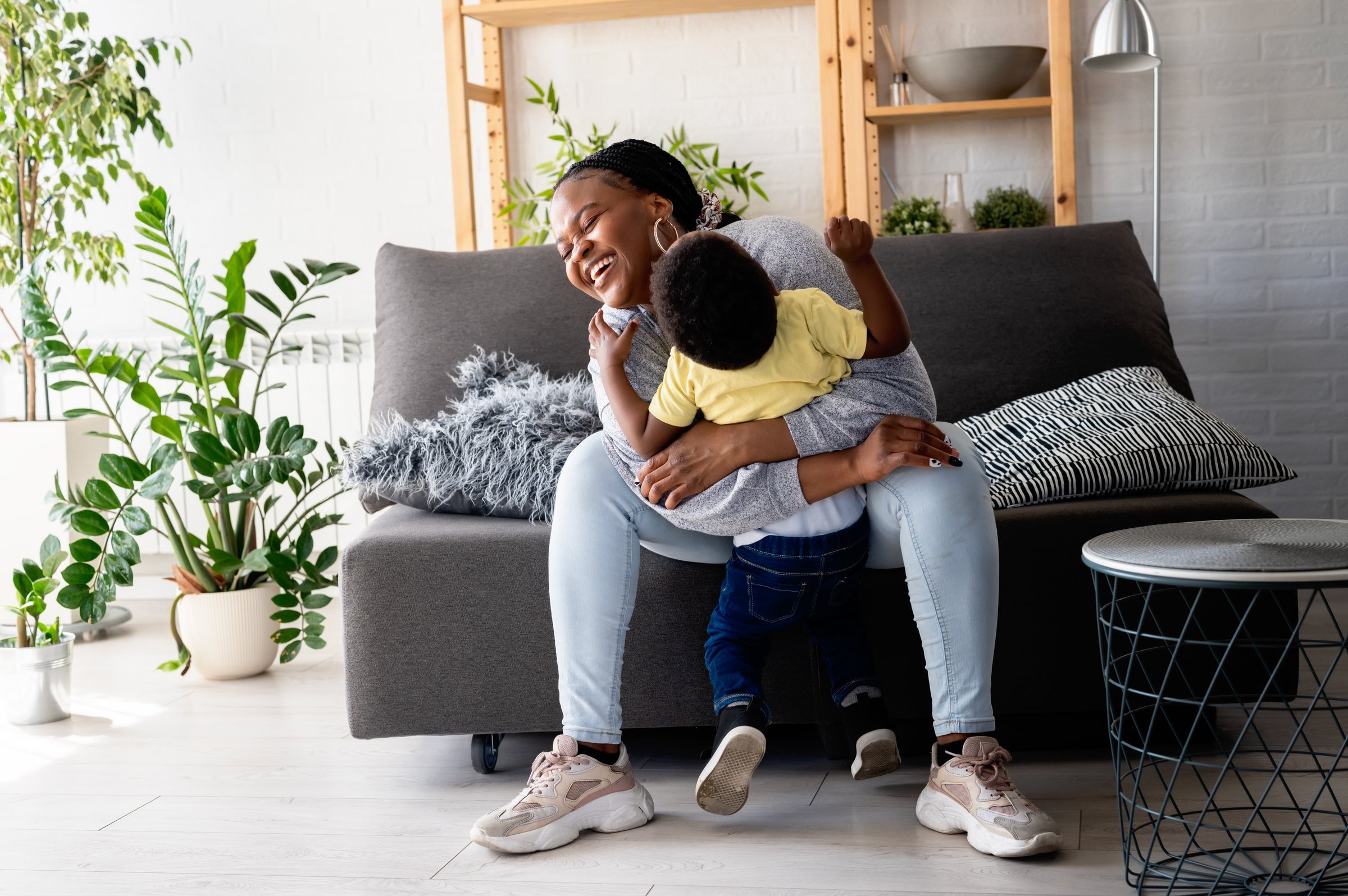 Cheerful African-American mother and son cuddling, laughing, and having fun at home. Family bonding time
