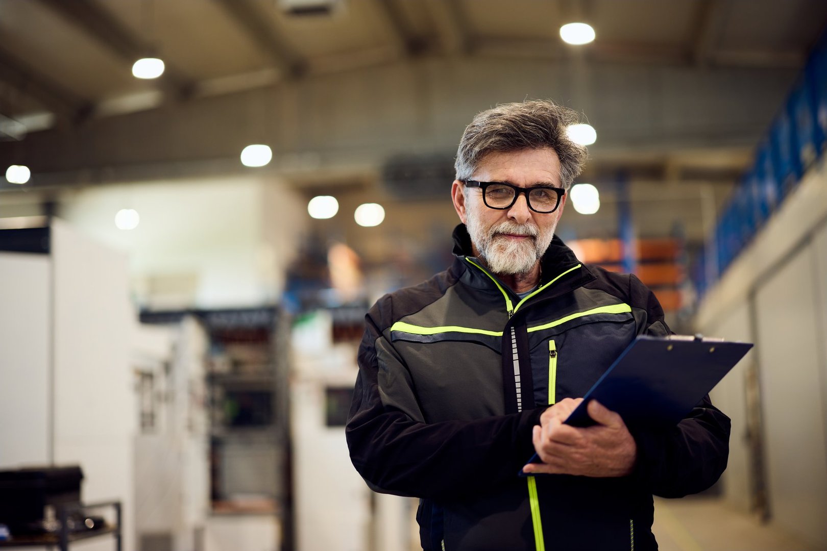 Professional engineer standing with a clipboard inside an industrial facility.