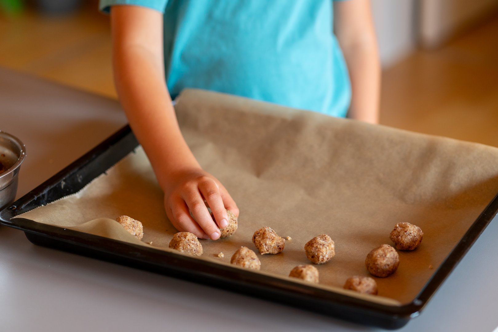 Children's hands make nut cookies and place them on a baking sheet