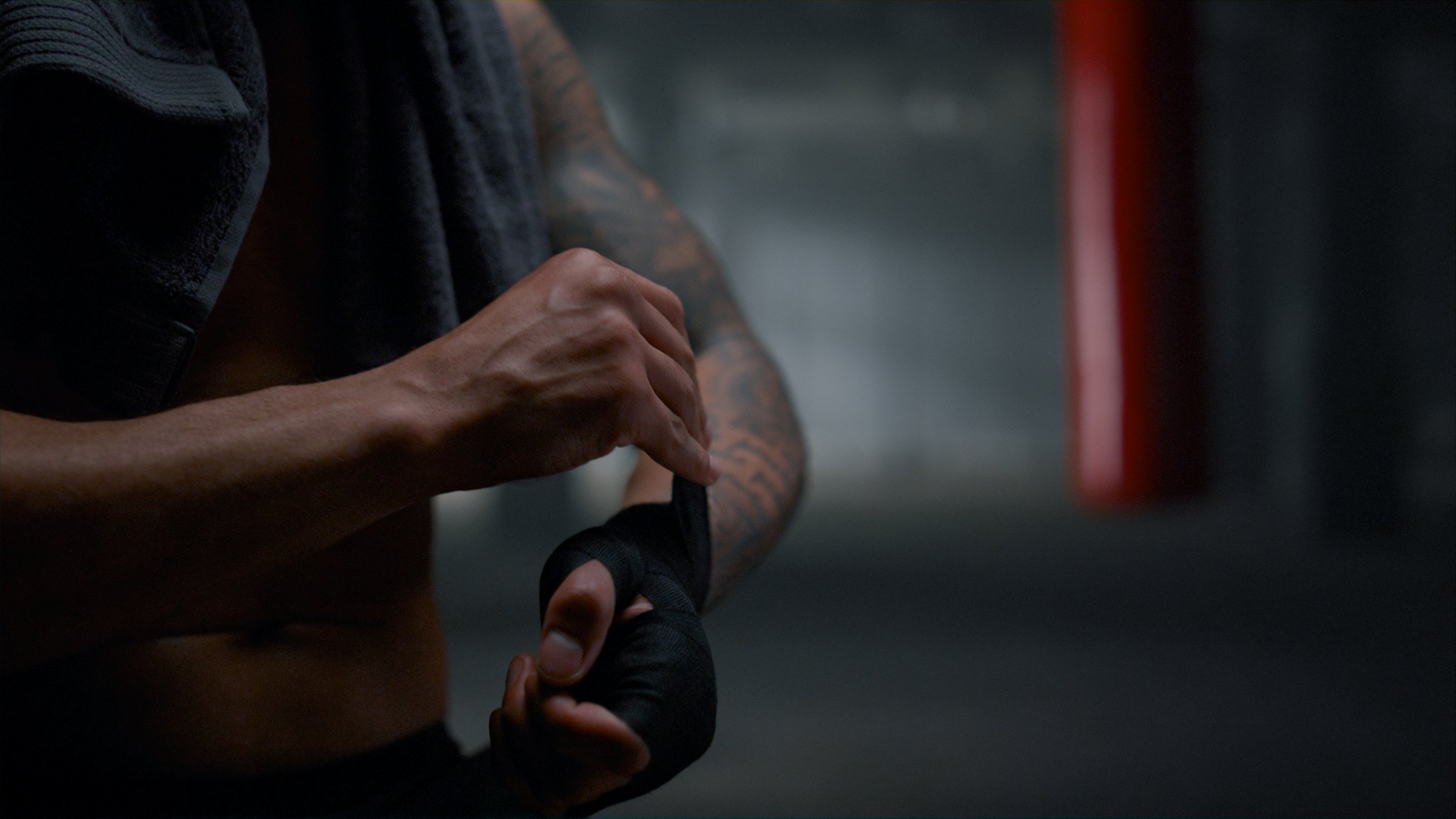 Closeup African American man pulling bandages on hands before boxing training. Athletic guy wrapping hands with punching wraps. Unrecognizable male fighter using boxing tapes for intense workout