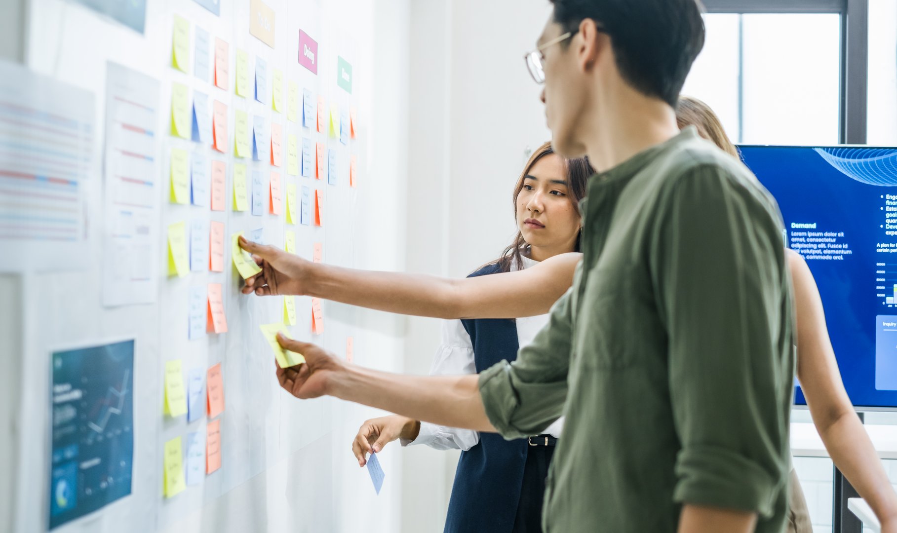brainstorming session, using sticky notes on a task board (kanban) to organize ideas and workflow in a modern office