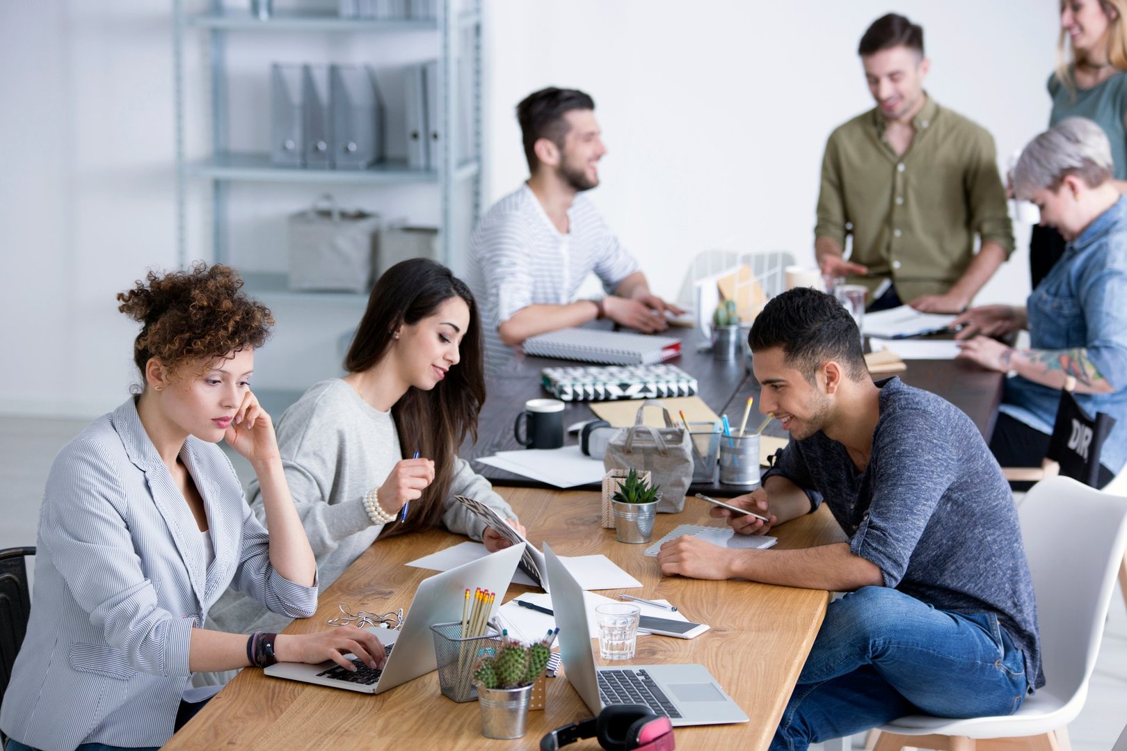 Young diverse female and male coworkers brainstorming ideas for a project by a table at a start-up office