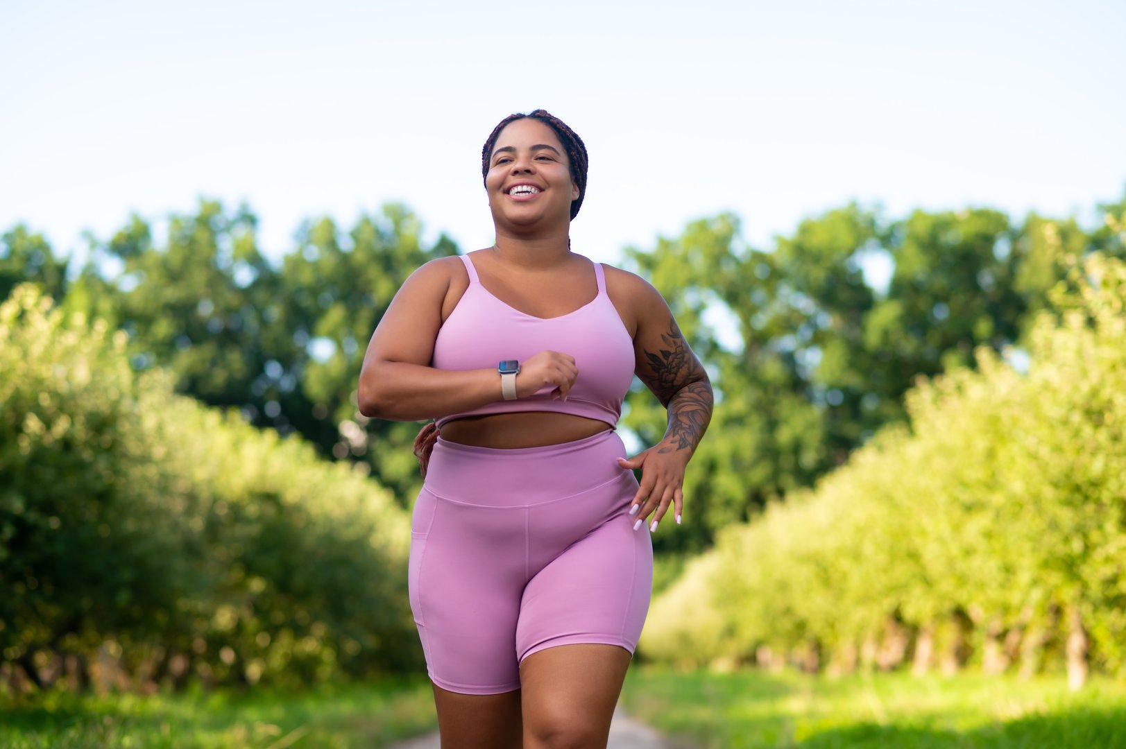 Body positive lifestyle. Plus size female athlete jogging on sports ground