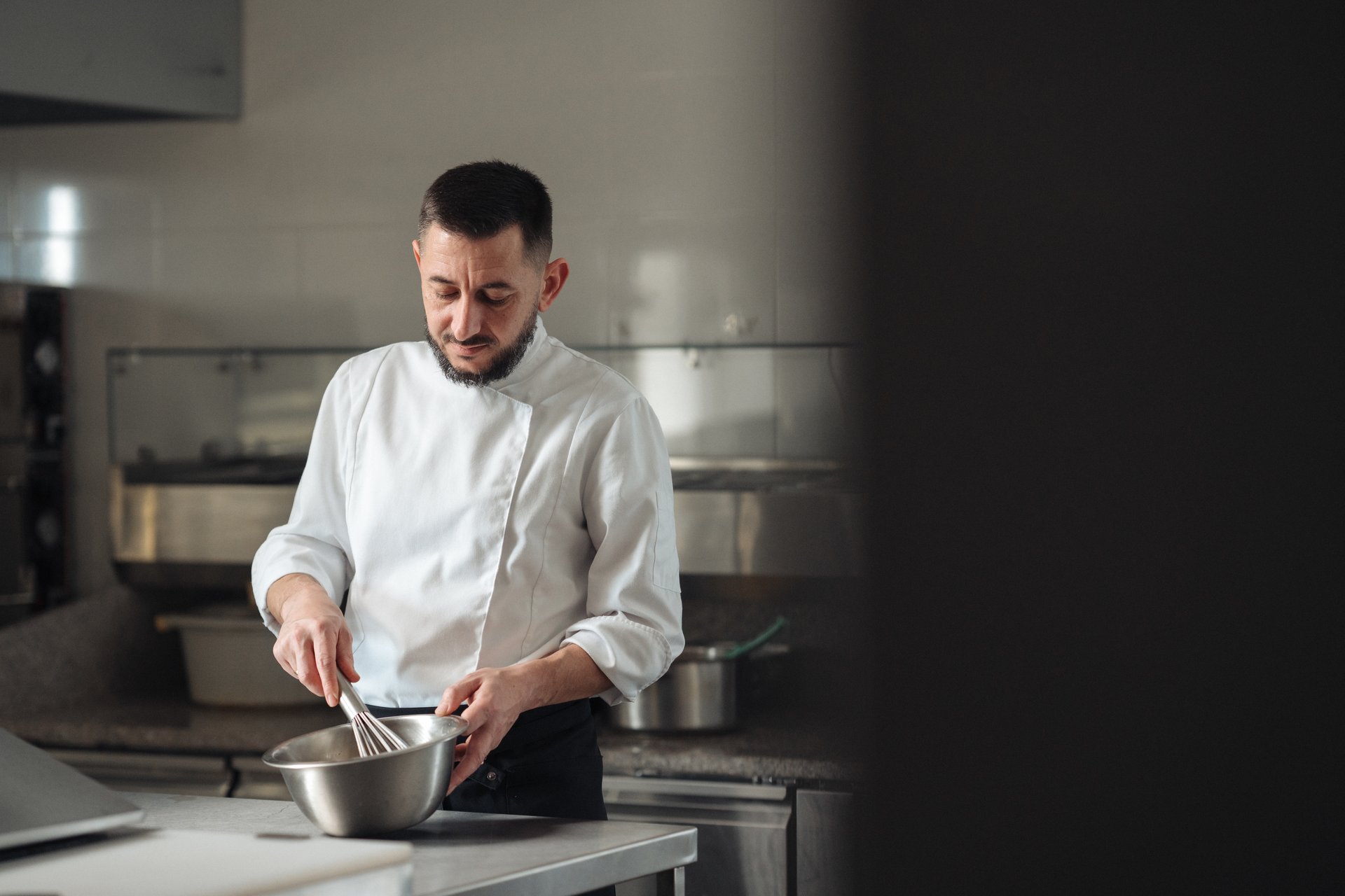 Pastry chef whisking batter in professional kitchen