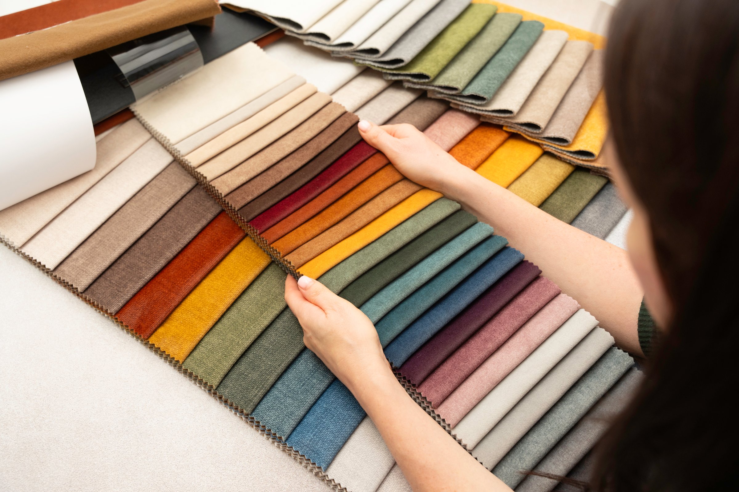 Person checking textile swatches for furniture upholstery, interior design, and home decoration ideas.