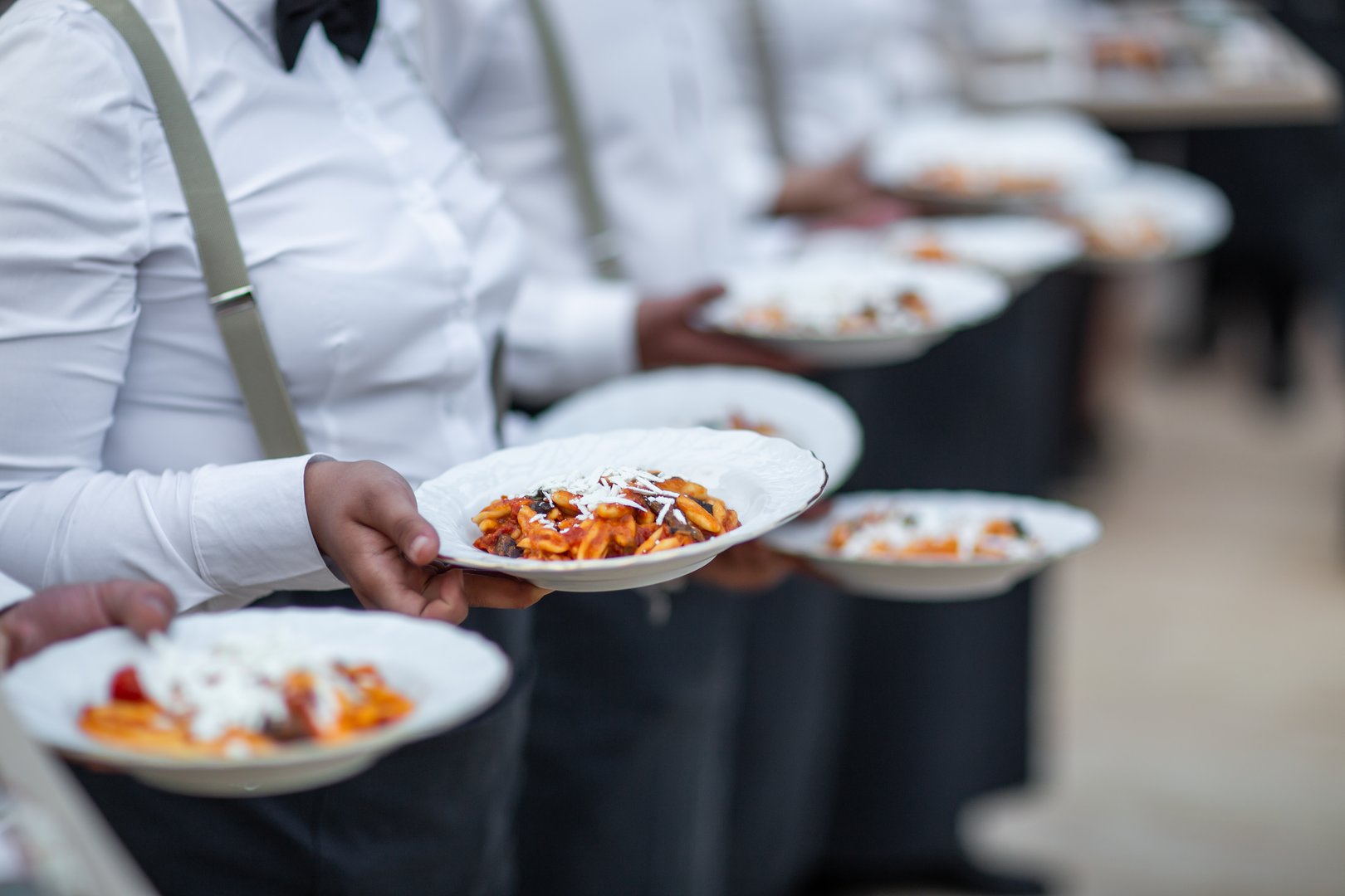 Waiters Serving Freshly Plated Pasta with Cheese Topping