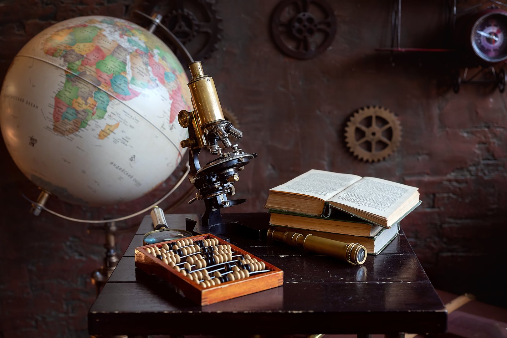 Globe, brass microscope, abacus, and open books on a wooden desk with a vintage background, symbolizing science and history