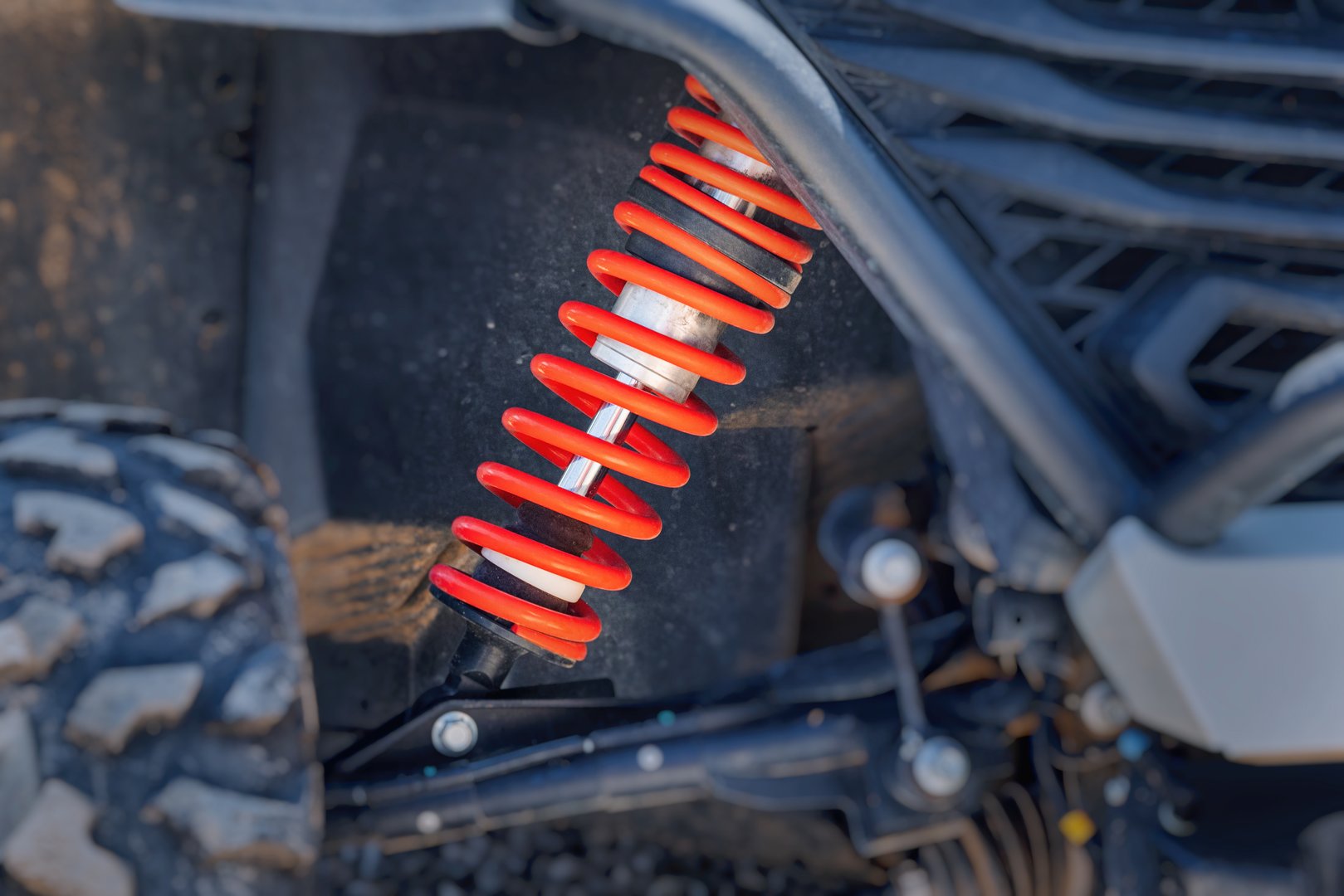 Close up showing an off road utility terrain vehicle - UTV - shock absorber, coil spring, and tire, highlighting durability and performance