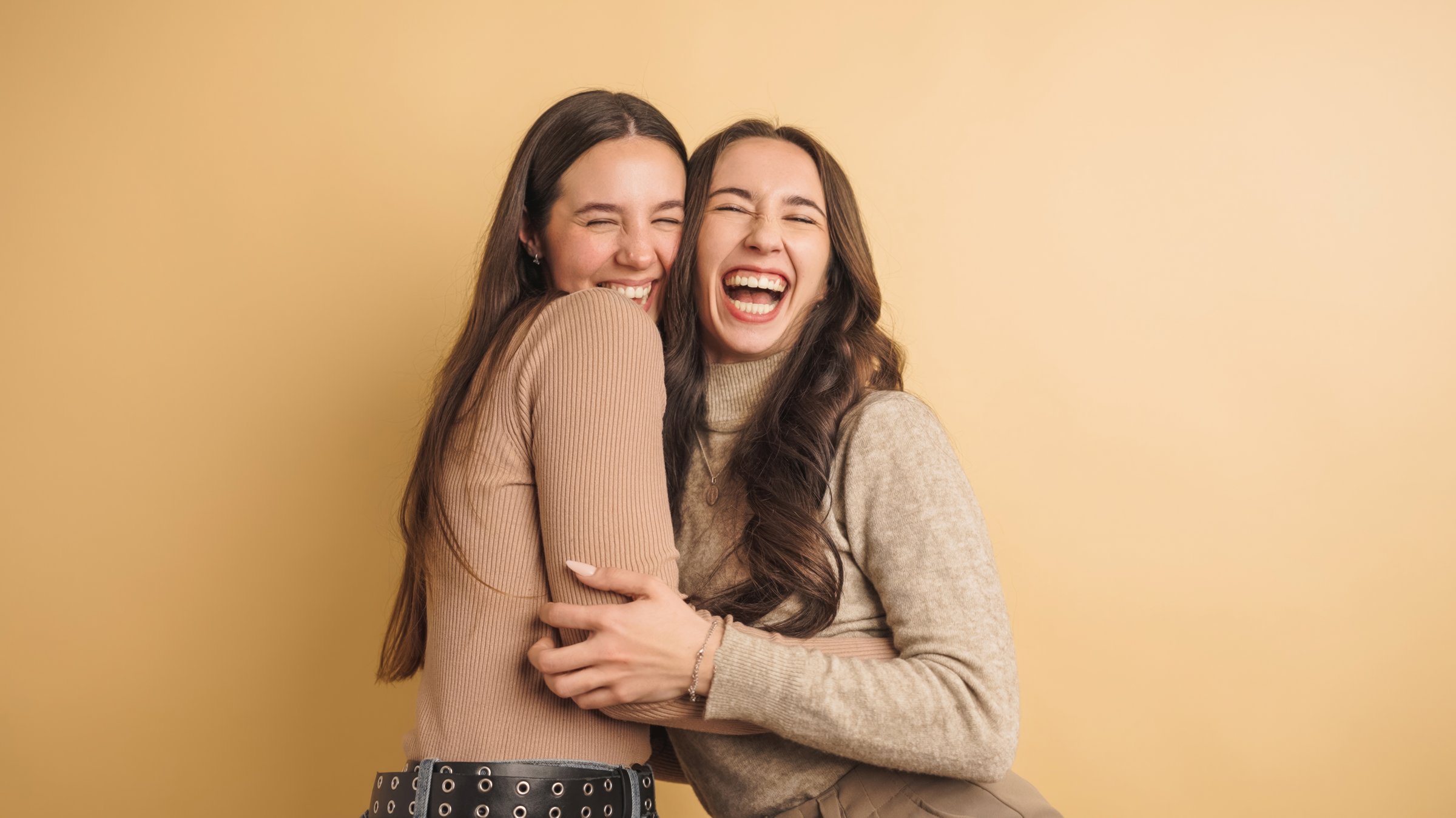 Two women share a joyful moment, laughing and embracing