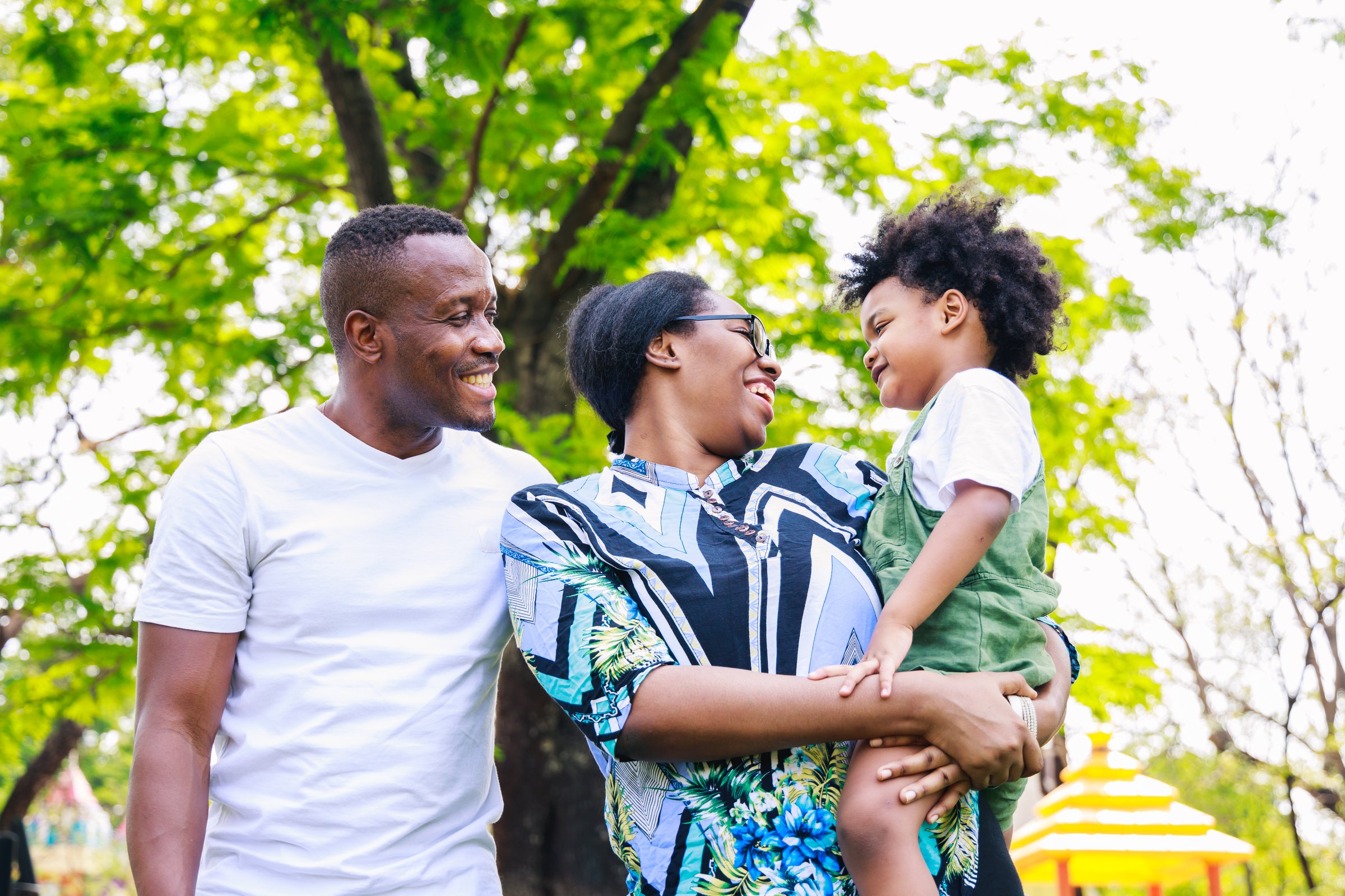 Portrait of African American family. Happy African American parent (Father, mother) and son are smiling together while standing in the park in the daytime in summer. Happy family concept.