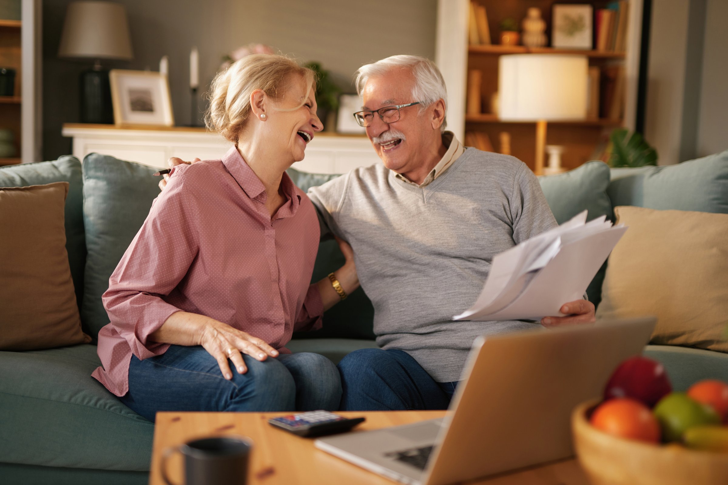 Smiling retired couple reviewing their finances and having fun together