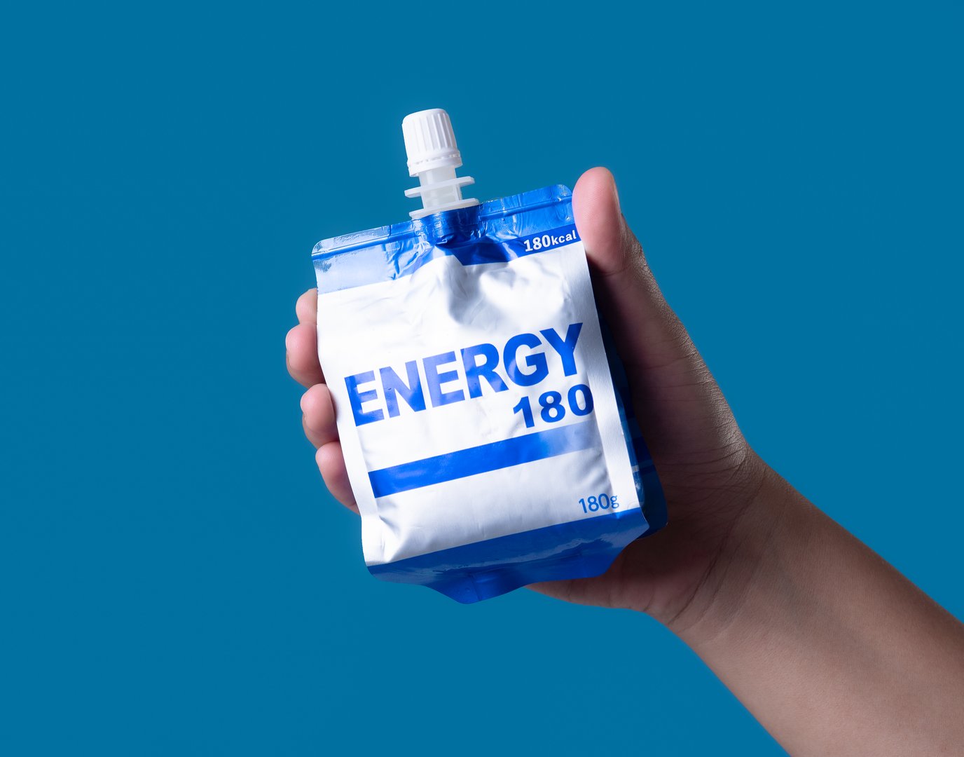 Hand hold energy sport gel packet on blue background
