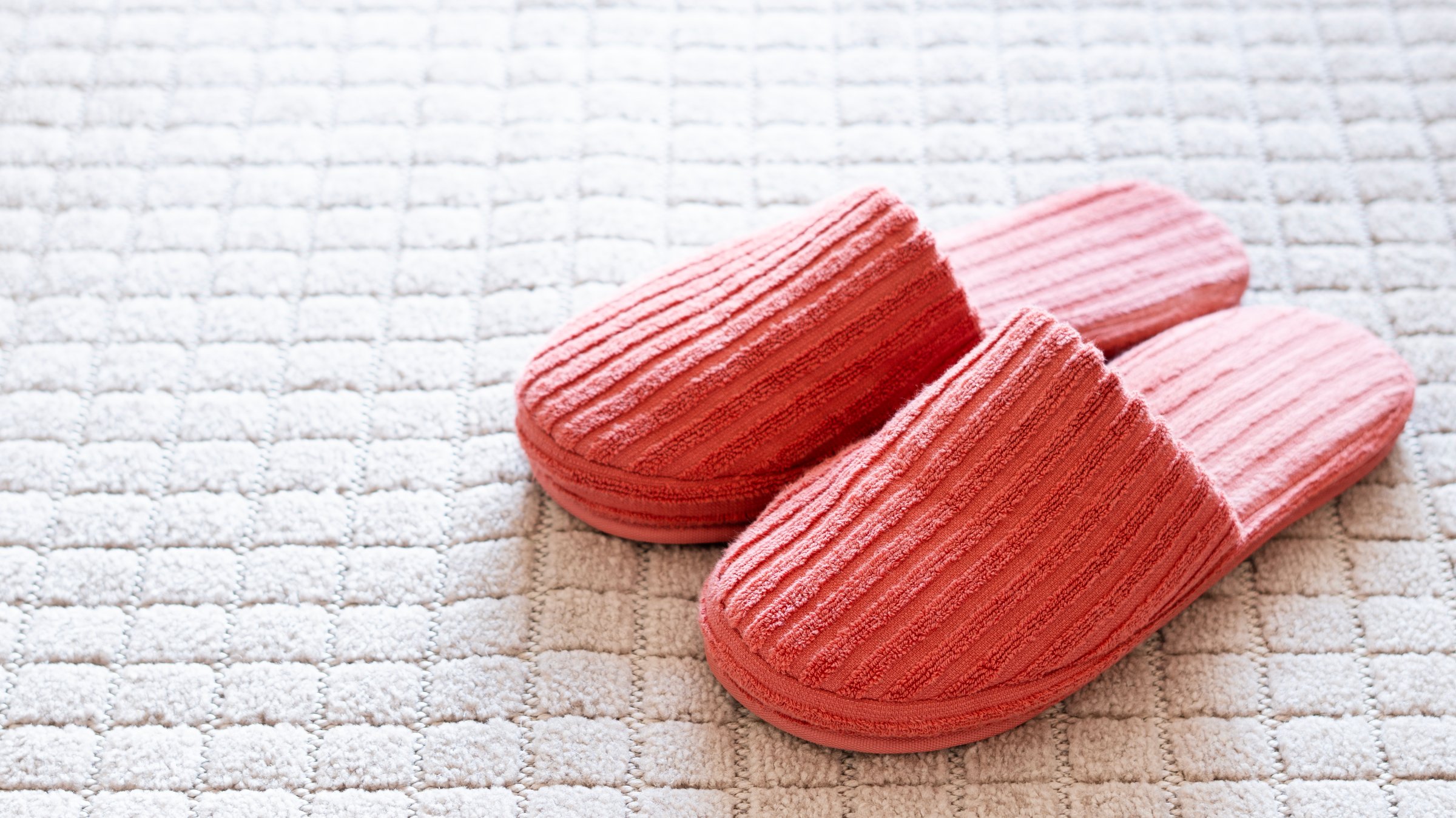 Slippers on soft white carpet in living room. Space for text