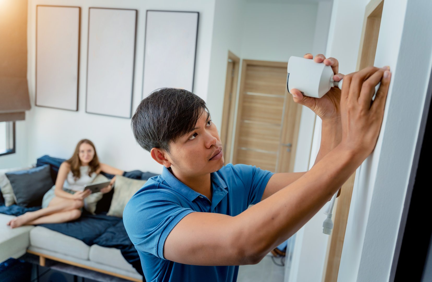 A technician installs a CCTV camera in a modern apartment