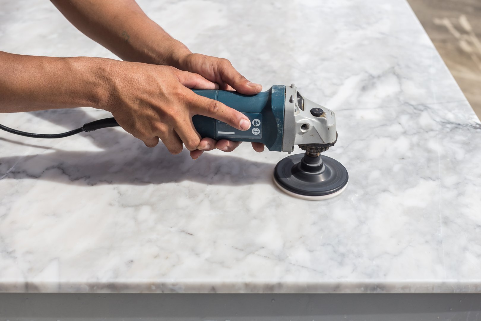 Man polishing marble stone table by small angle grinder