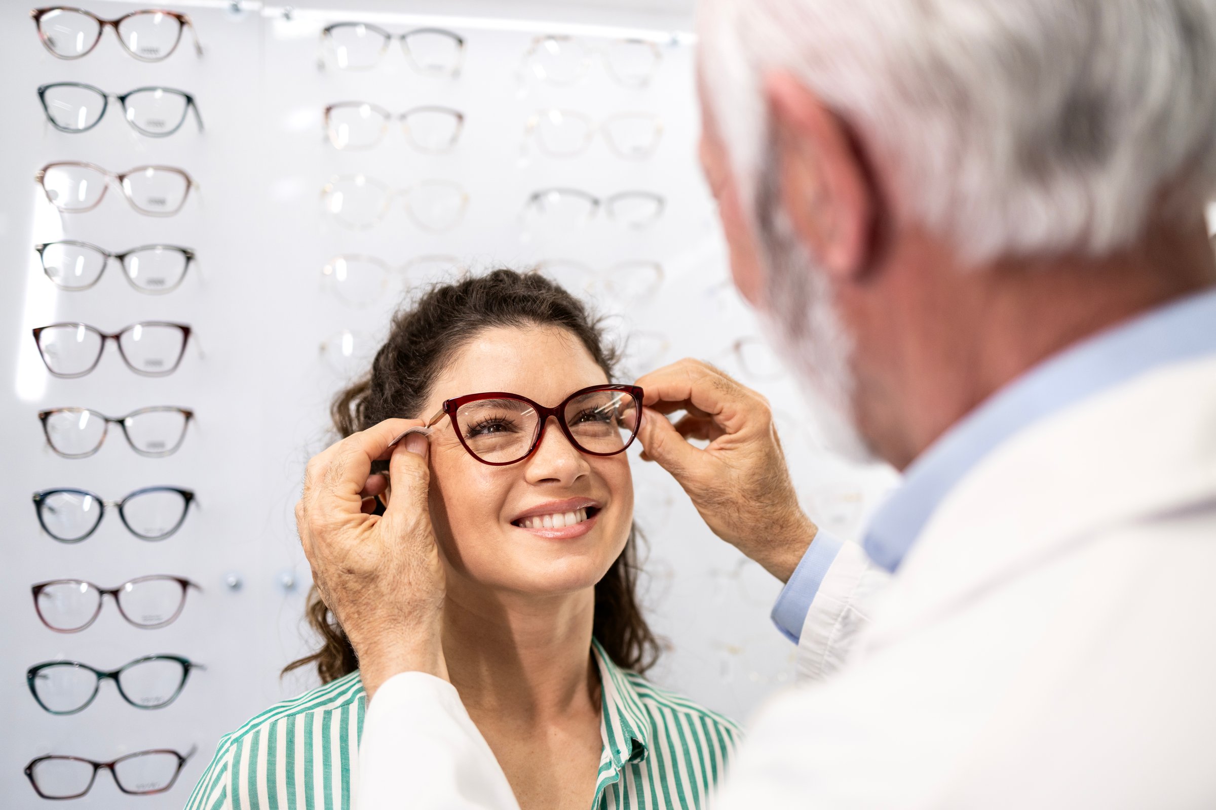 Woman buying new eyeglasses with help of experienced senior ophthalmologist.
