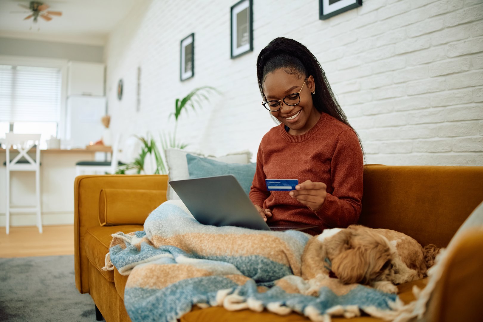 Happy African American woman shopping online while relaxing at home.