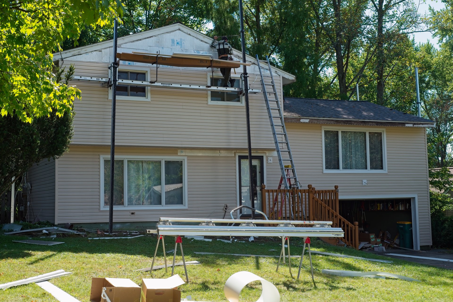 Twinsburg, OH, USA - October 3, 2024: A home siding replacement project nears completion with new siding installed on all but the very top of a split-level suburban house.