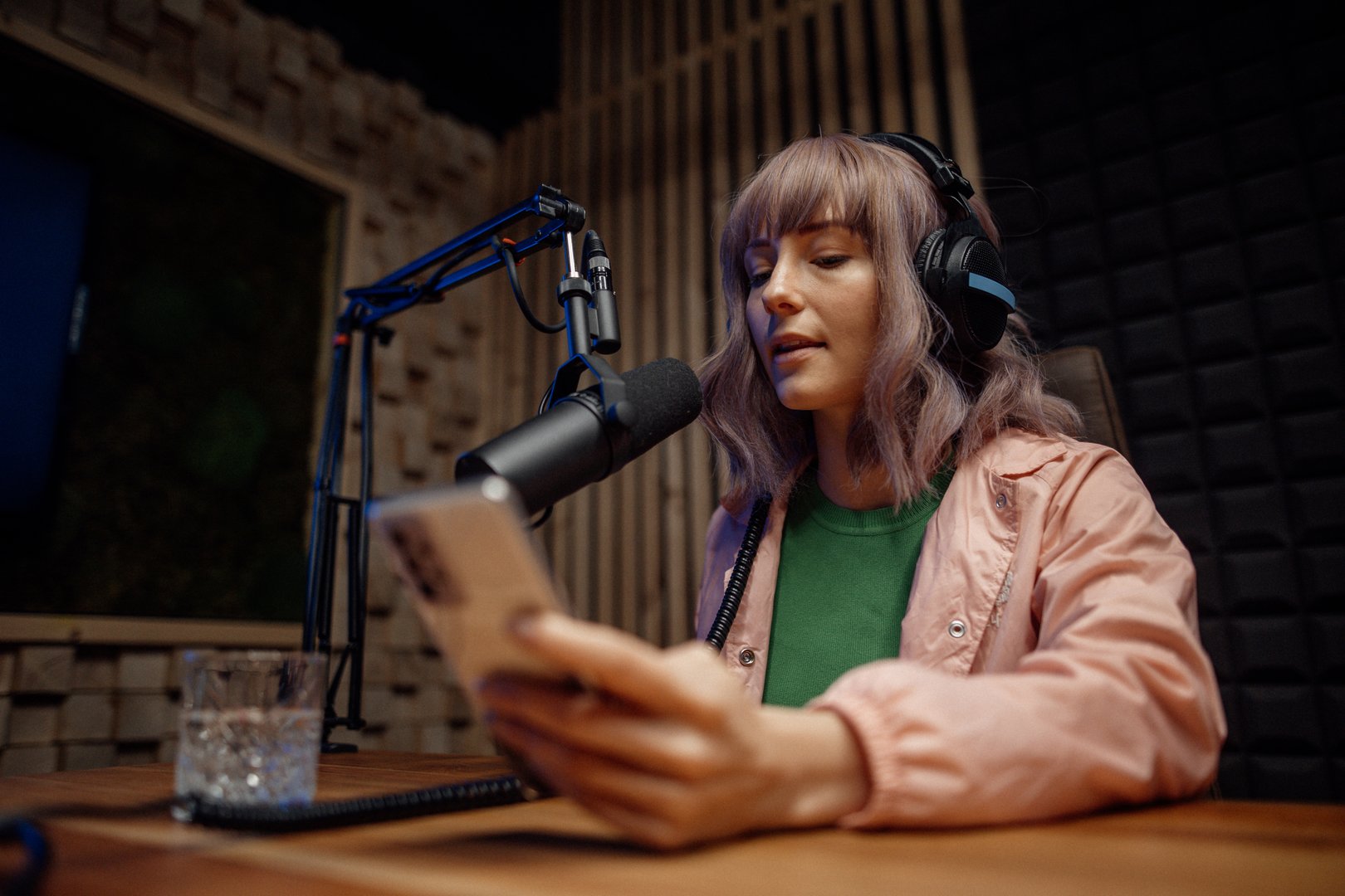 A young woman host talking to microphone and interviewing a man for aradio podcast, using smartphone.