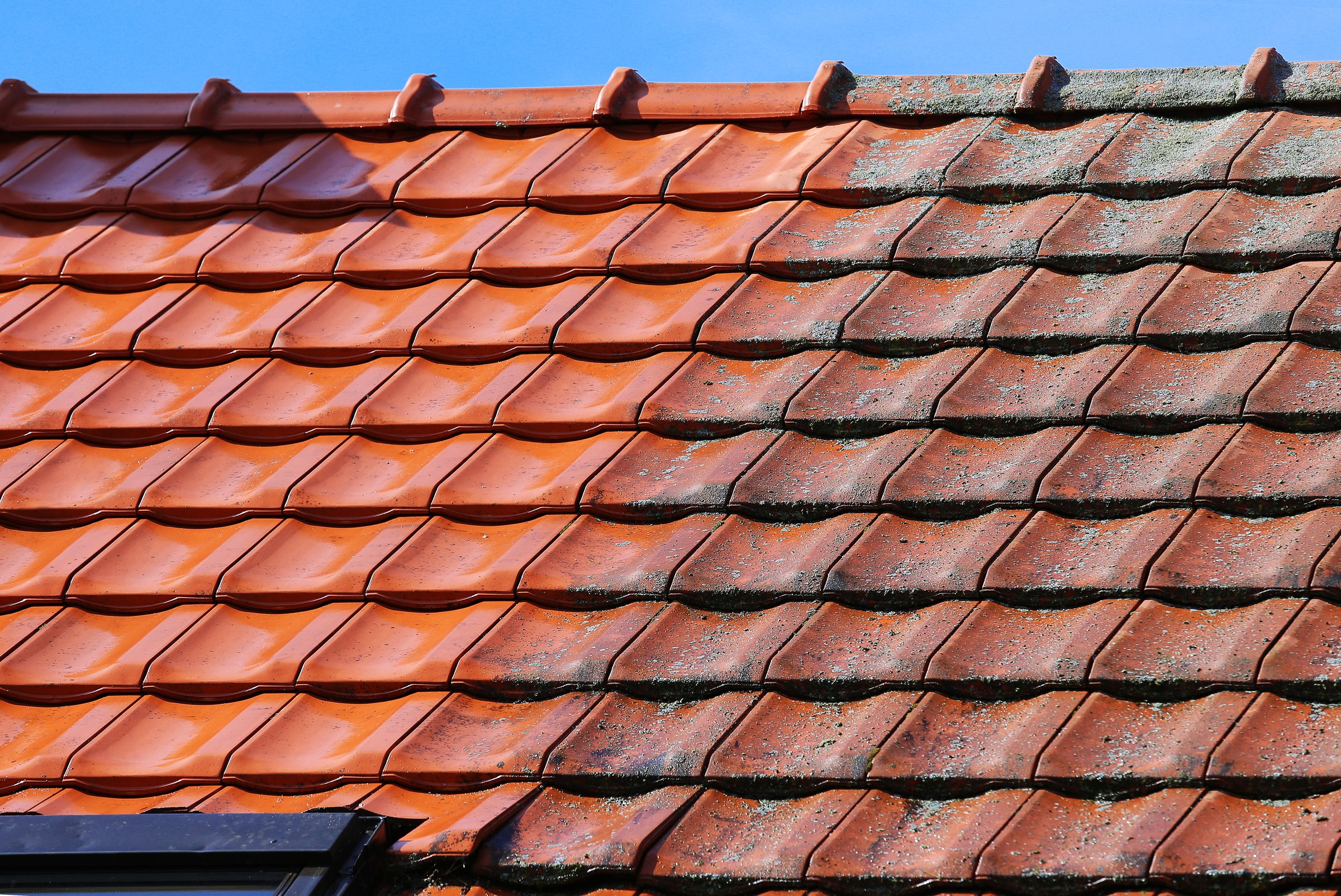 Workers cleaning the roof of moss and dirt with a high pressure cleaner. Roof background before and after cleaning.