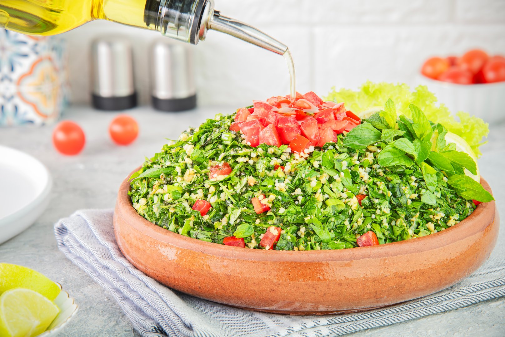 Arabic Cuisine; Pouring olive oil on traditional Mediterranean Tabbouleh salad. It's made with finely chopped parsley, tomatoes, mint, onion and bulgur wheat.