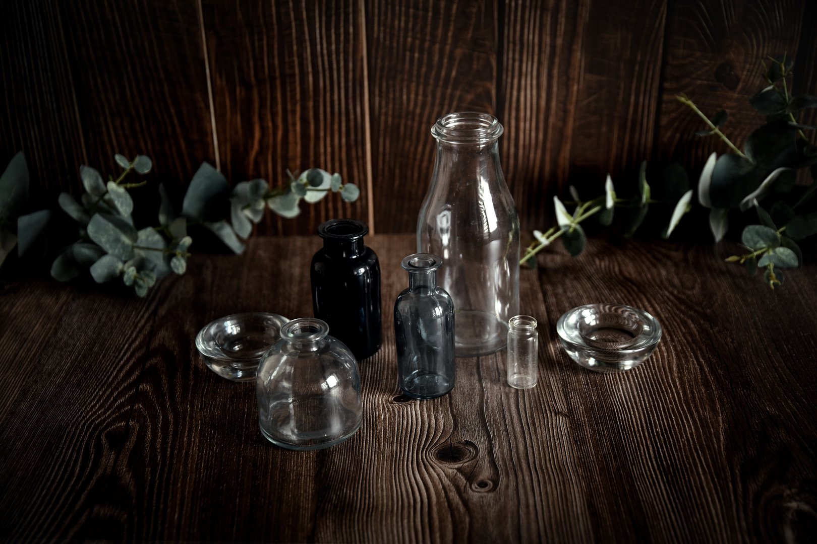 depicts various glass bottles and small bowls located on a wooden table.