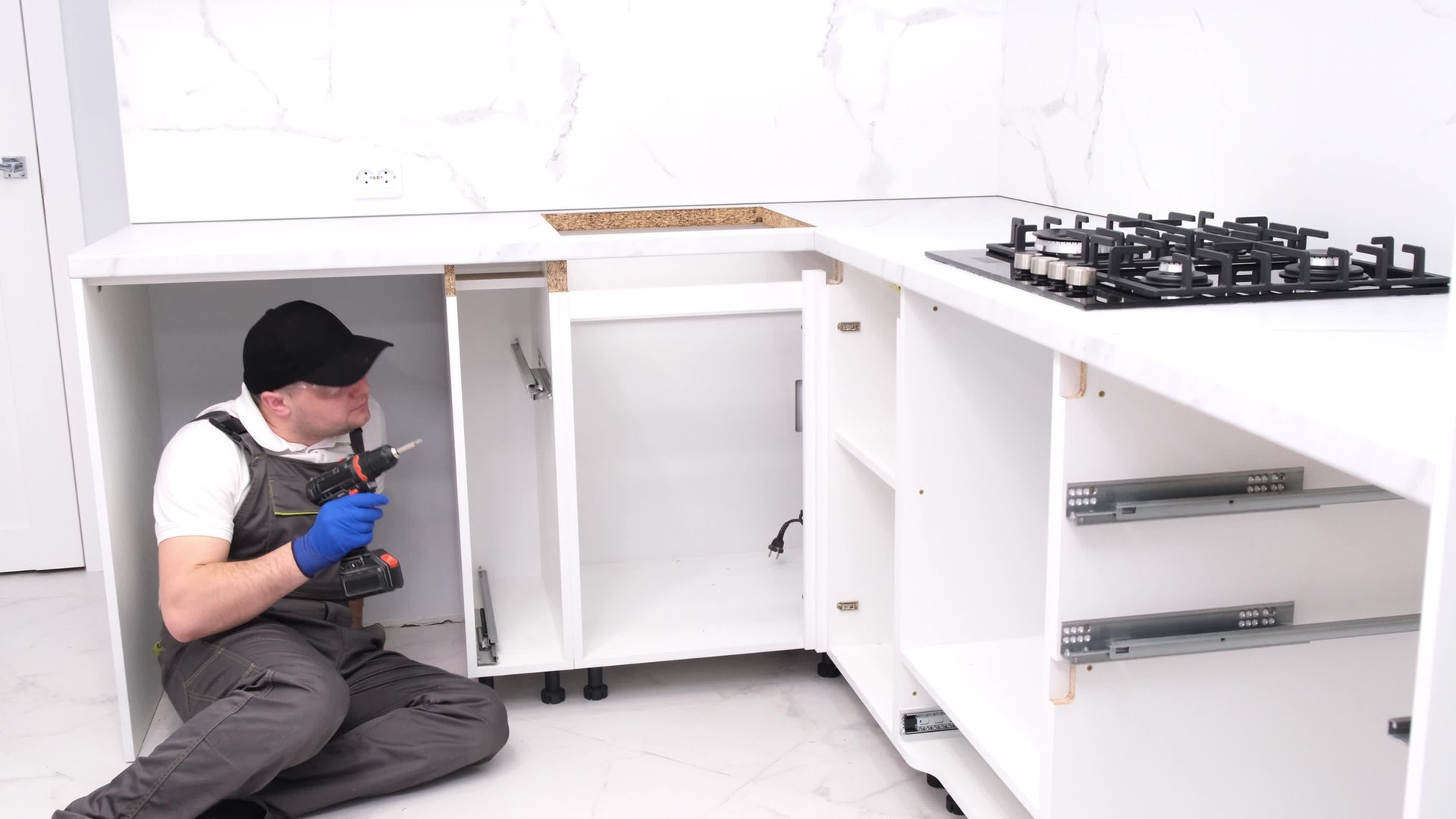 Male repairman assembles furniture using an electronic screwdriver. Professional installation of furniture