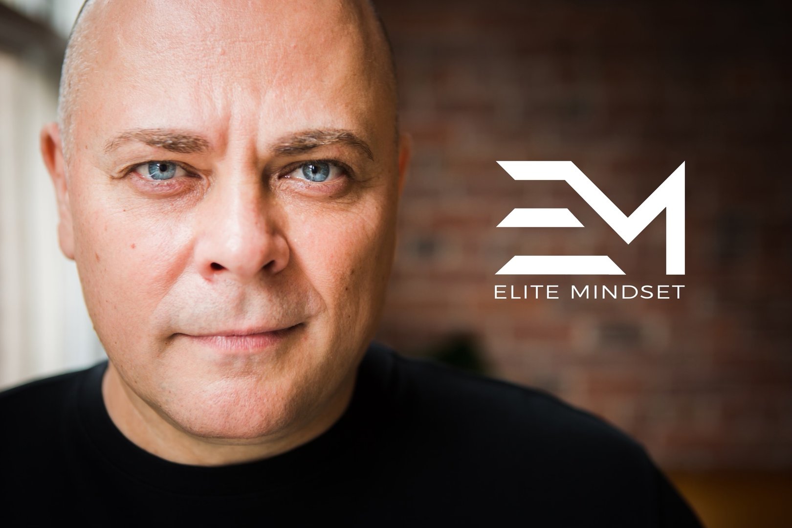 Close-up of a person with a logo "Elite Mindset" in white text on a brick wall background.