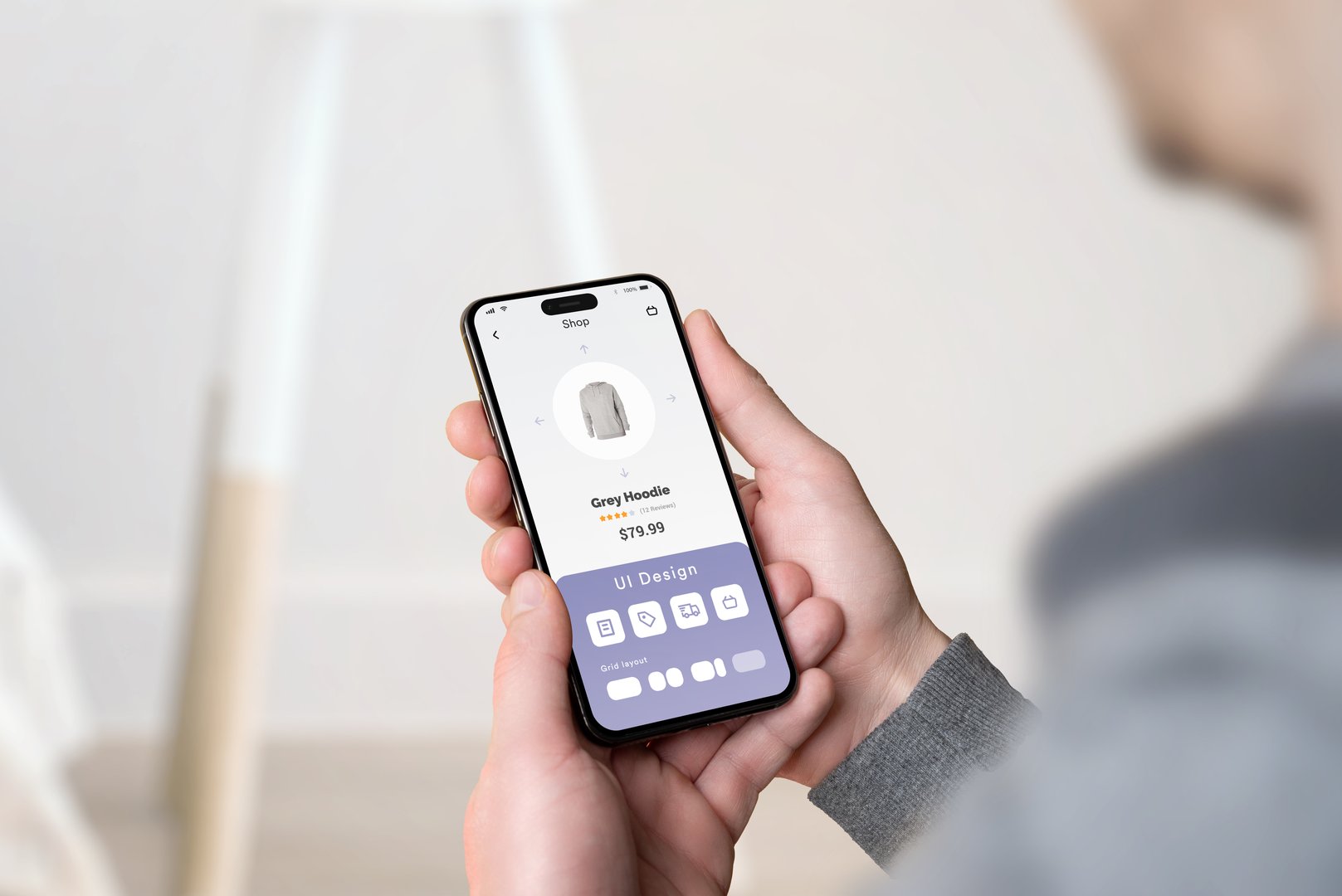 Hand holding smartphone with a UI design editor app open, showcasing the process of creating a mobile application interface in a digital design studio