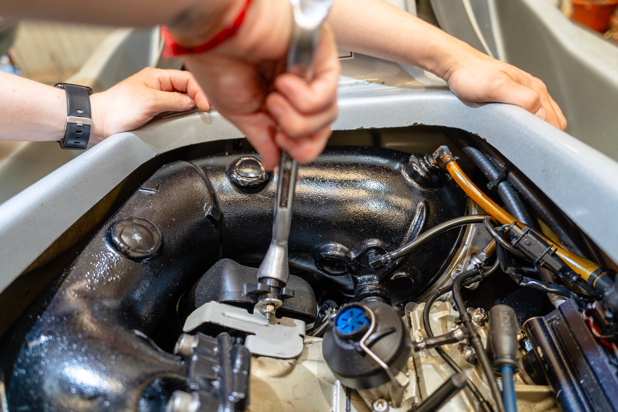 Mechanic working on a personal watercraft engine, using a wrench to tighten bolts