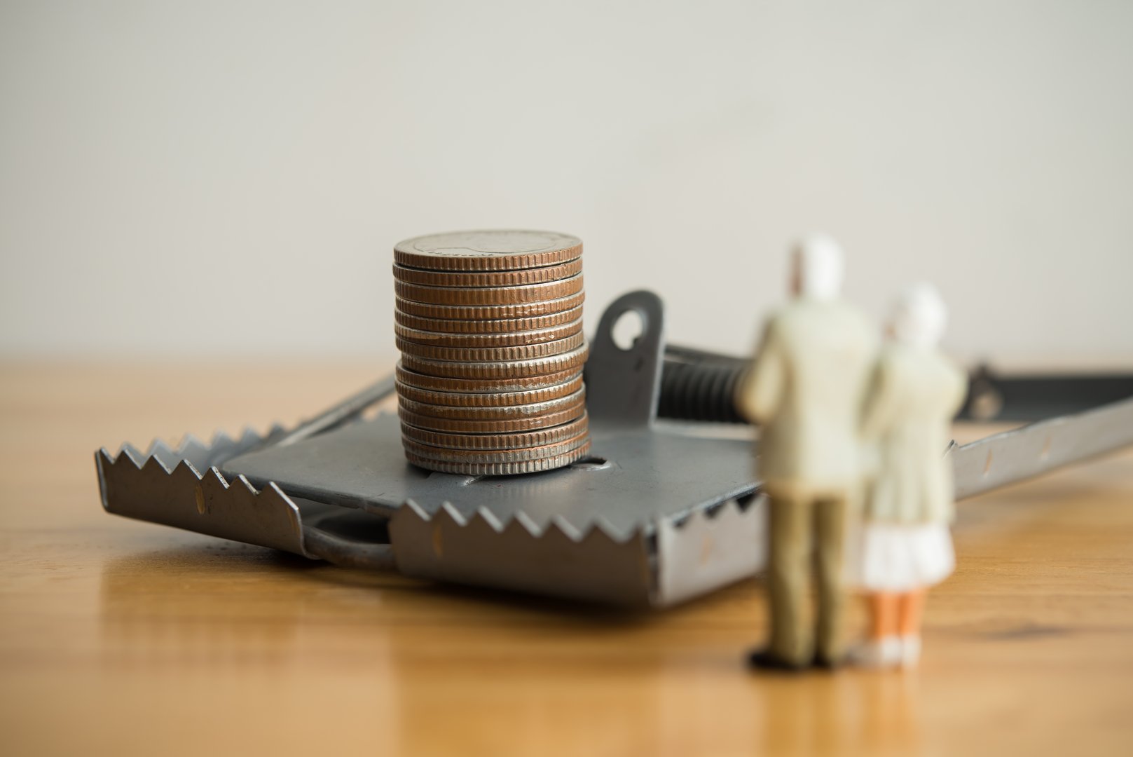 Elderly spouses looking at money coins in rat trap. Senior couple loss money from a scammer, investing scam, financial deception, online or offline swindler, blackmail, social issues and so on concept
