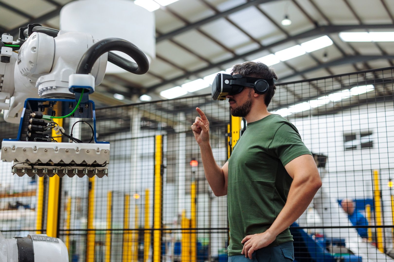 Factory worker using virtual reality headset controlling robotic arm, exploring the future of industrial automation and smart manufacturing