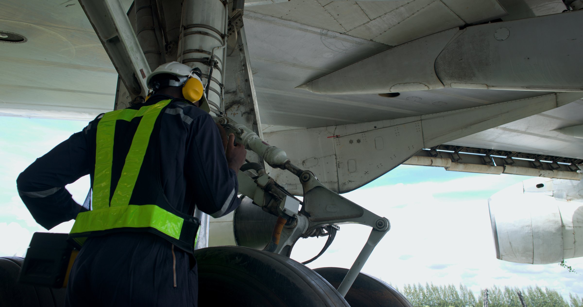 The black male aircraft mechanics use hand tools to work on inspection and do maintenance of an airplane, Aircraft technician examining a plane in the hangar