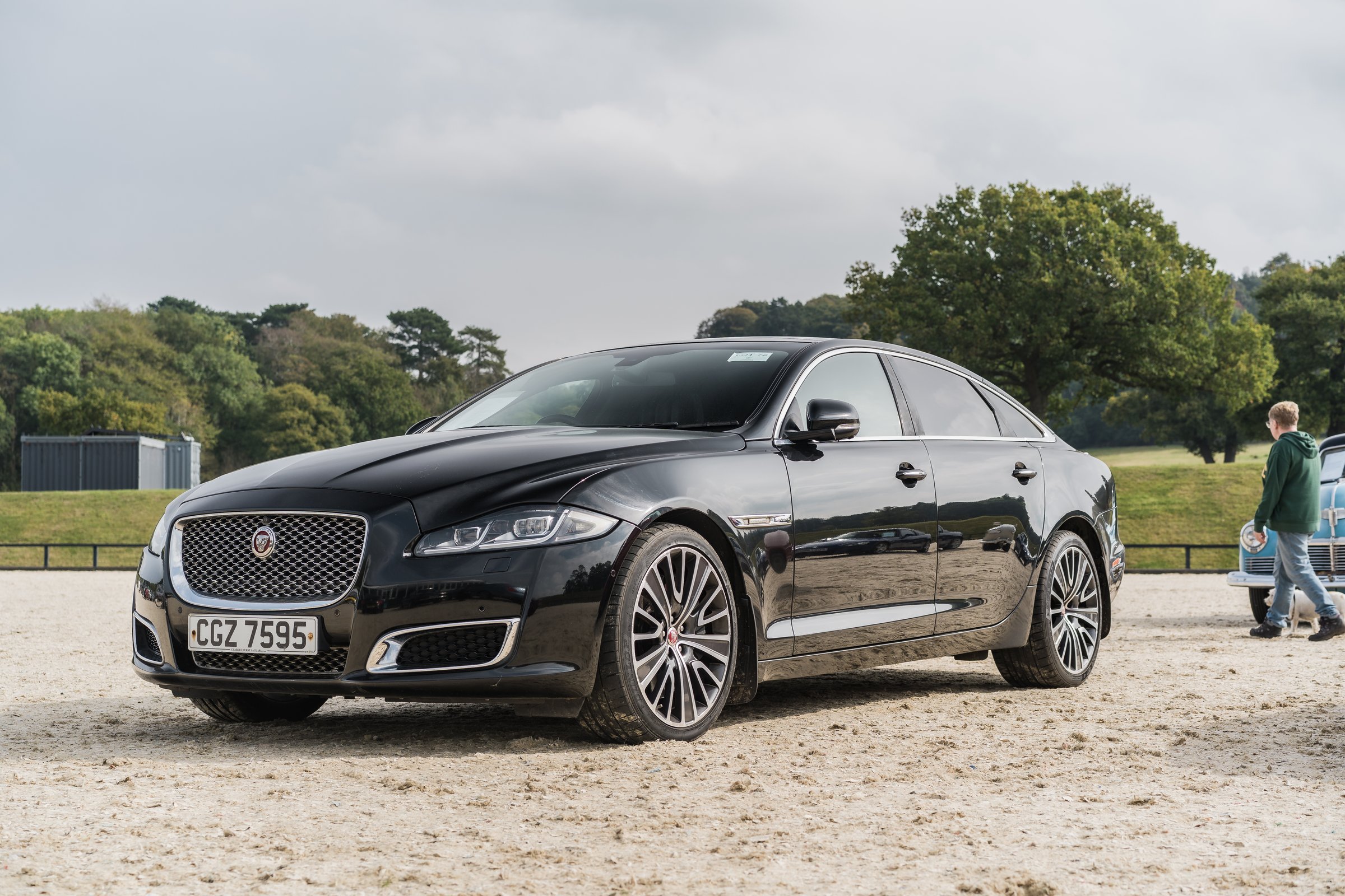 Chester, Cheshire, England, September 27th 2025. A black Jaguar XJ is displayed at the Chester Car Auction, with people looking at cars in the backdrop.
