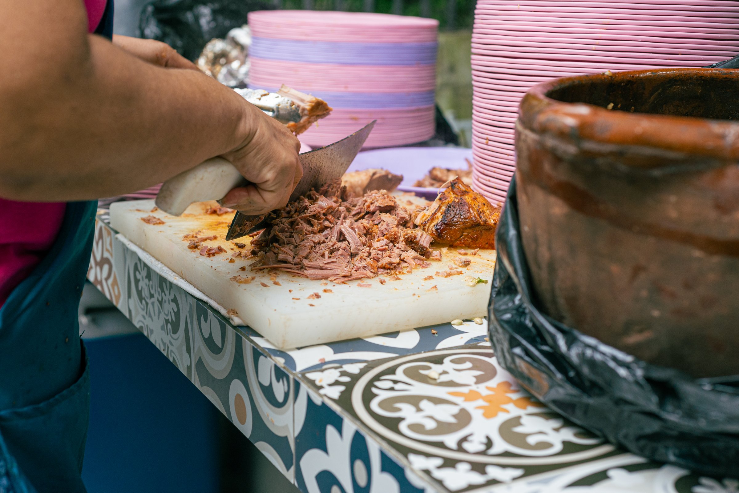 Unrecognizable woman serving meat on a plate during a Mexican party. Birria, typical Mexican food.