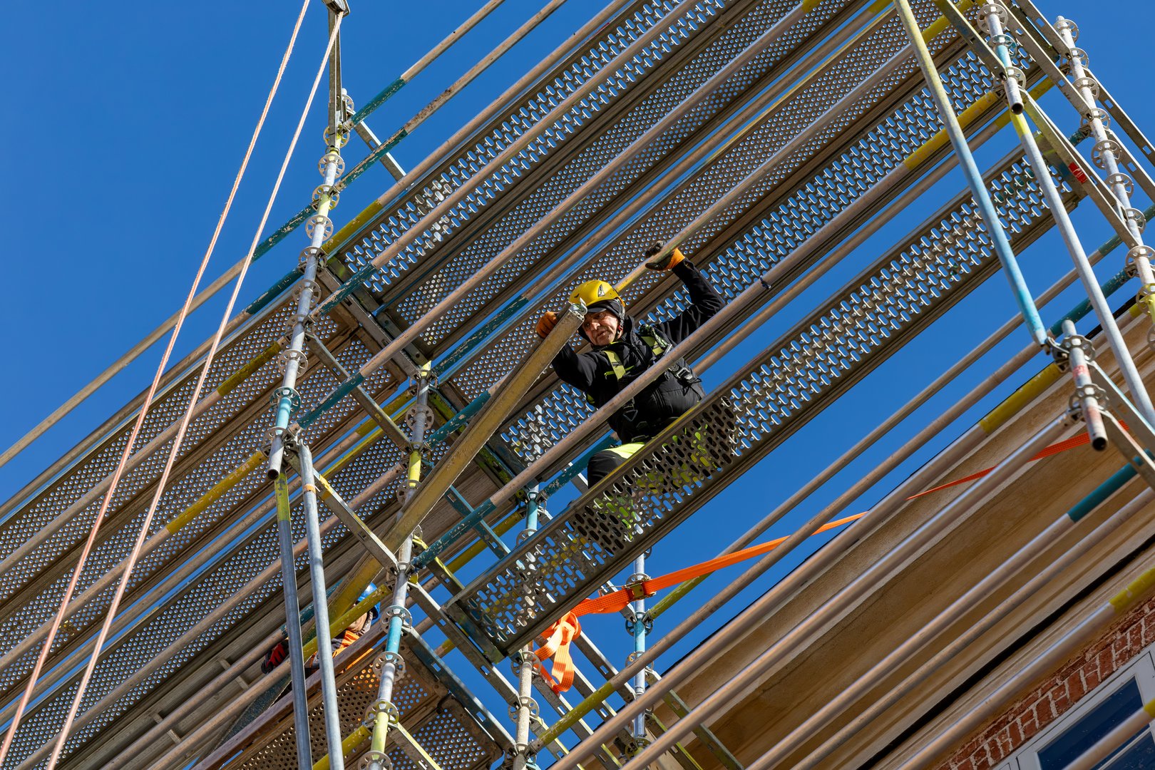 Mariefred, Sweden Oct 23, 2024 A workman with a harness builds a scaffolding on an old building.