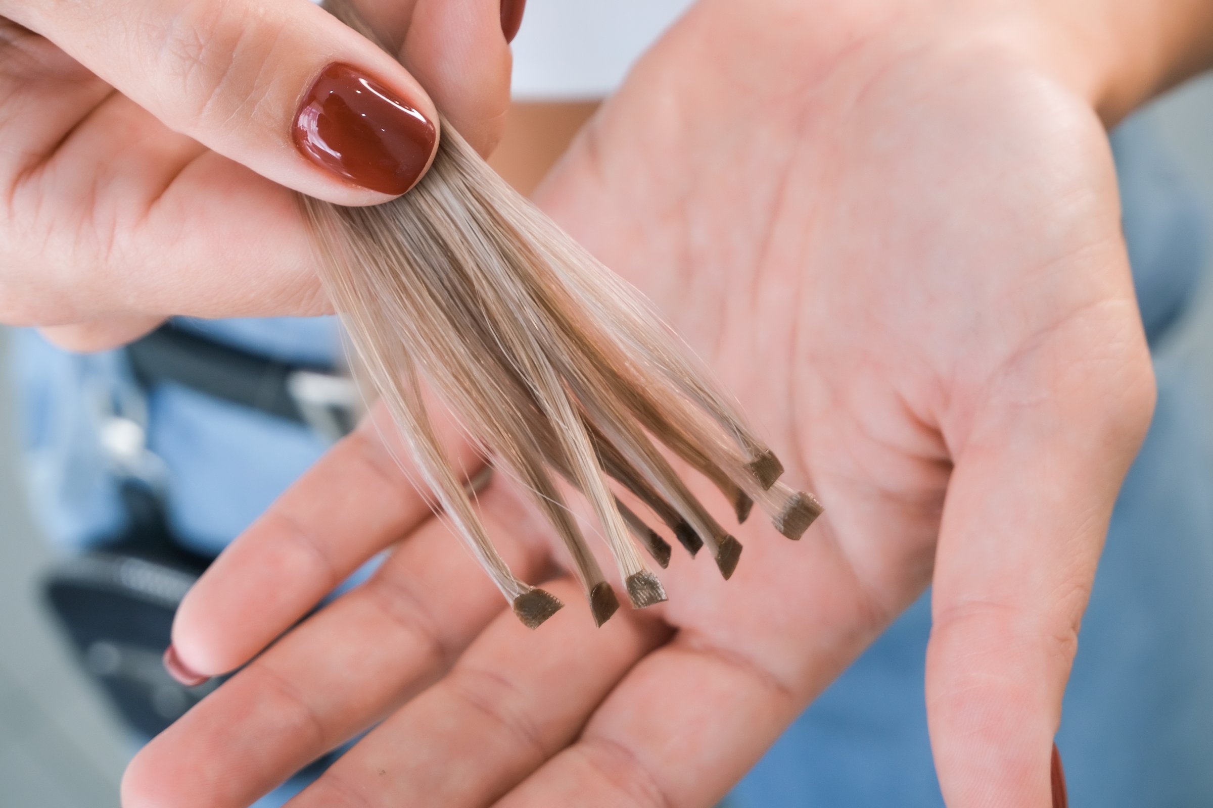Hair extension. Hair strands with capsules in hand. Preparing for hair extensions in a beauty salon