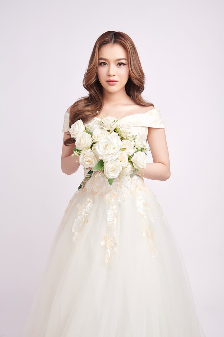 Beautiful young asian woman in wedding dress holding bouquet on white background,