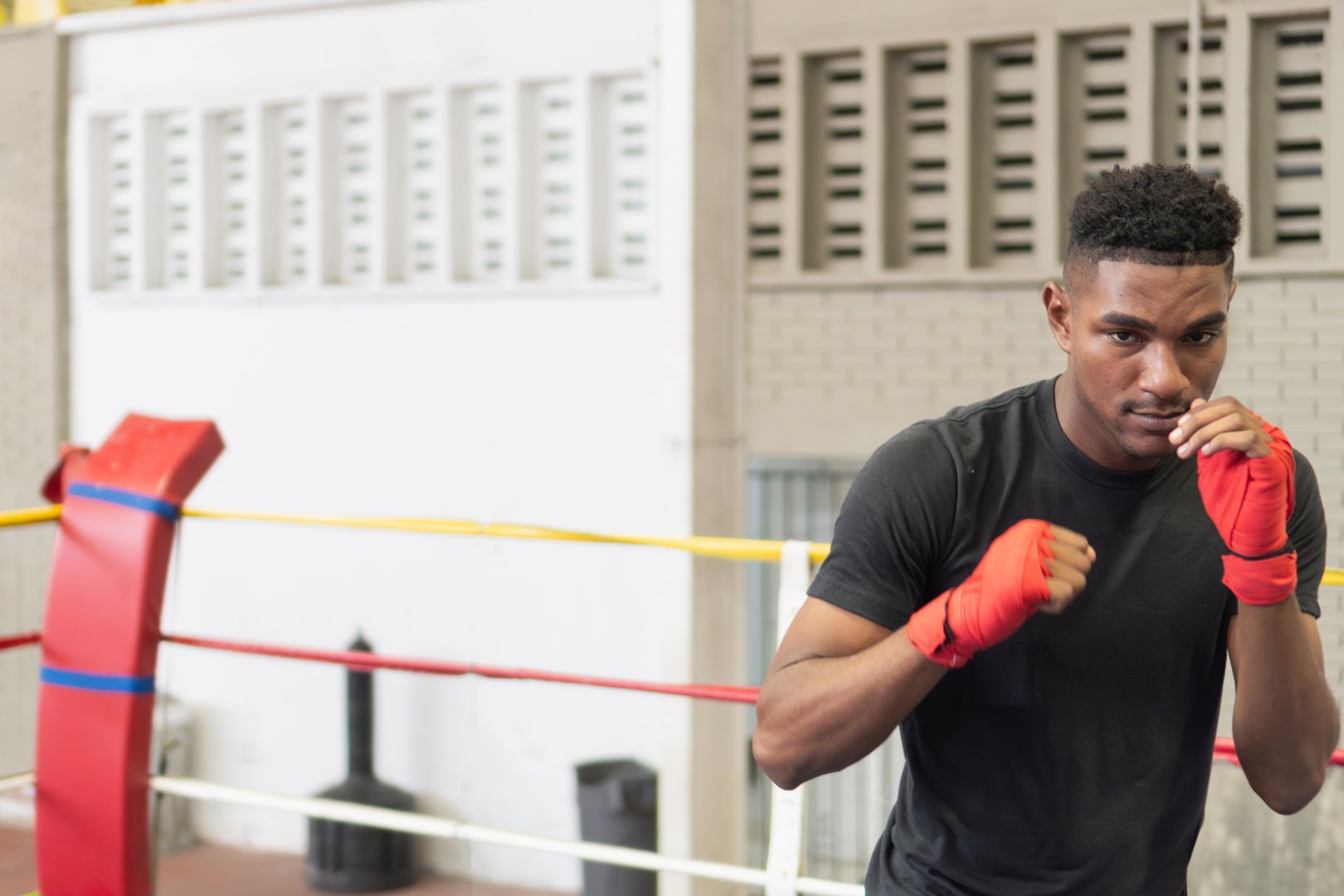 Determined young black man practicing boxing inside a boxing ring, focused on his training