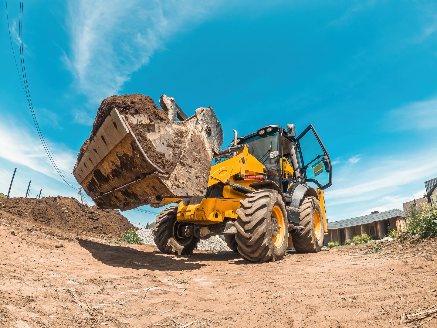 Big yellow tractor loader levels plot of land for new building. Construction site preparation. Landscape leveling