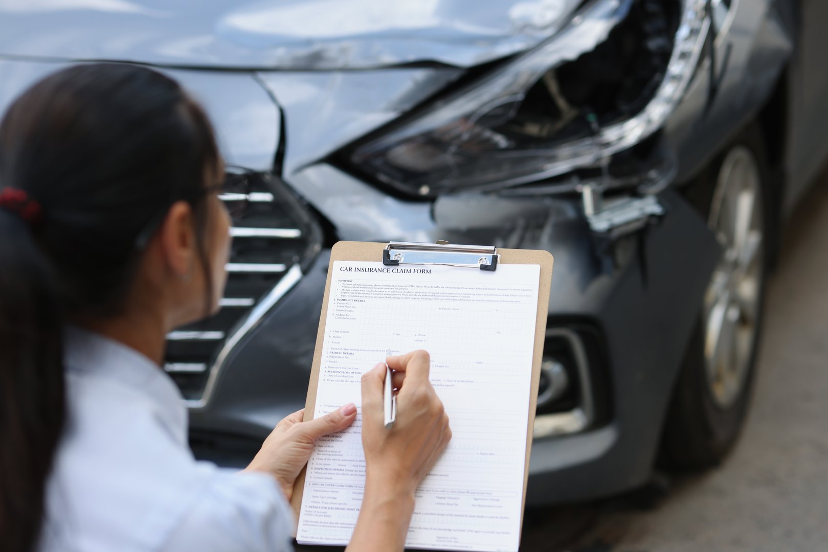 Woman insurance agent fills out insurance form for car damage after traffic accident. Inspection and damage assessment concept