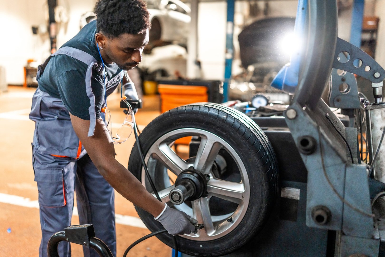 Professional mechanic balancing a car tire on advanced machinery in a modern auto repair shop, showcasing skill and precision in automotive service