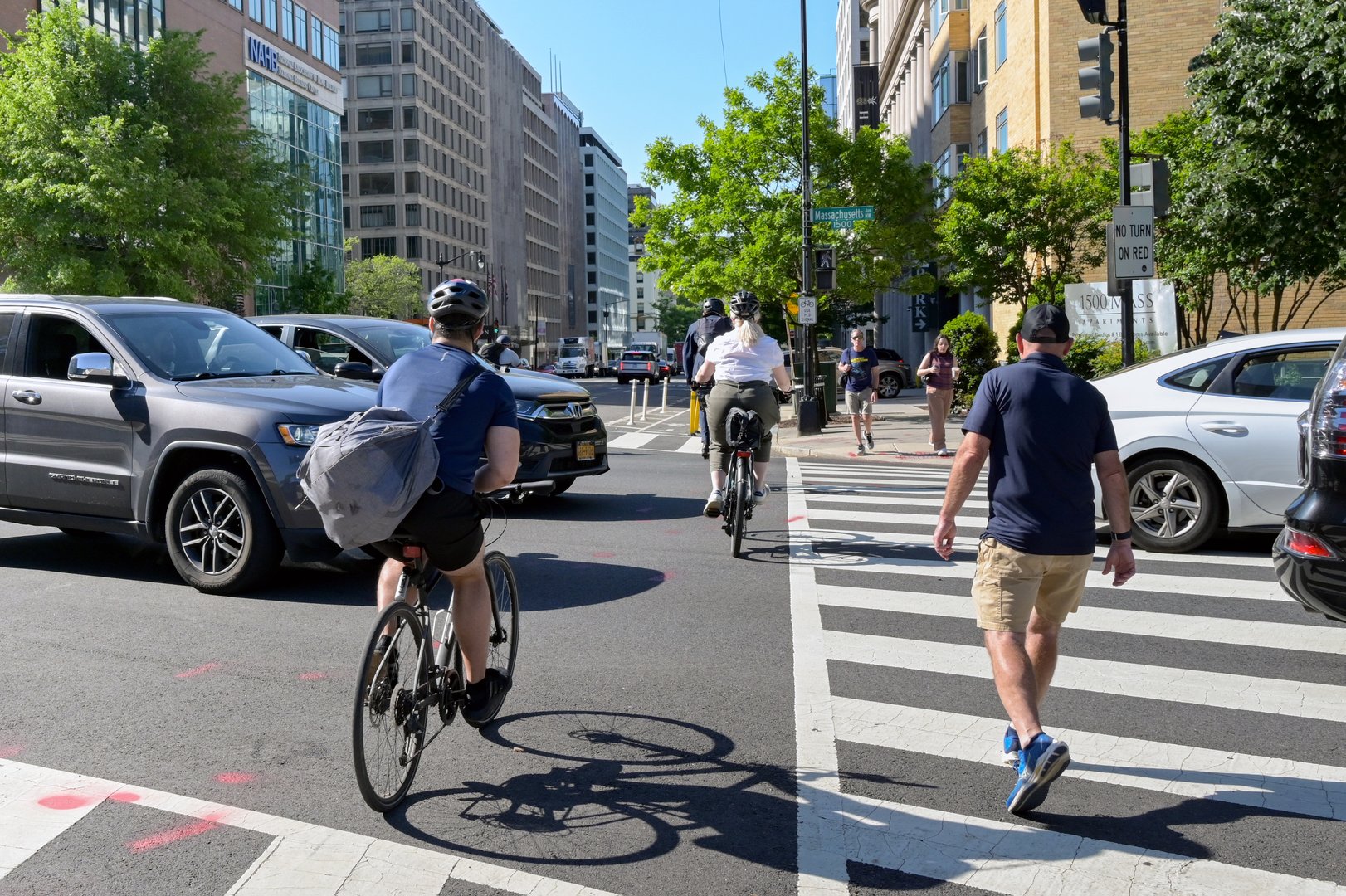 Washington DC, USA - 1 May 2024: Cyclists and pedestrians between cars across a road junction on their way to work in central Washington DC