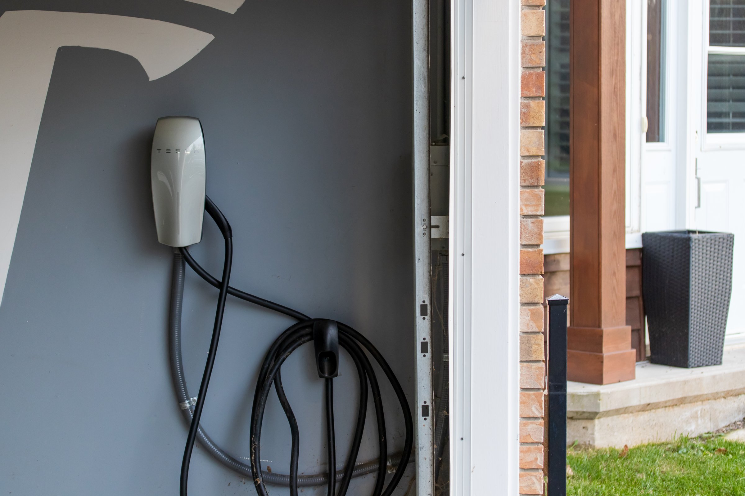 A Tesla electric vehicle charger is installed inside a car owner's garage for their Tesla electric vehicle. Tesla, an American electric vehicle and clean energy company based in Austin, Texas.