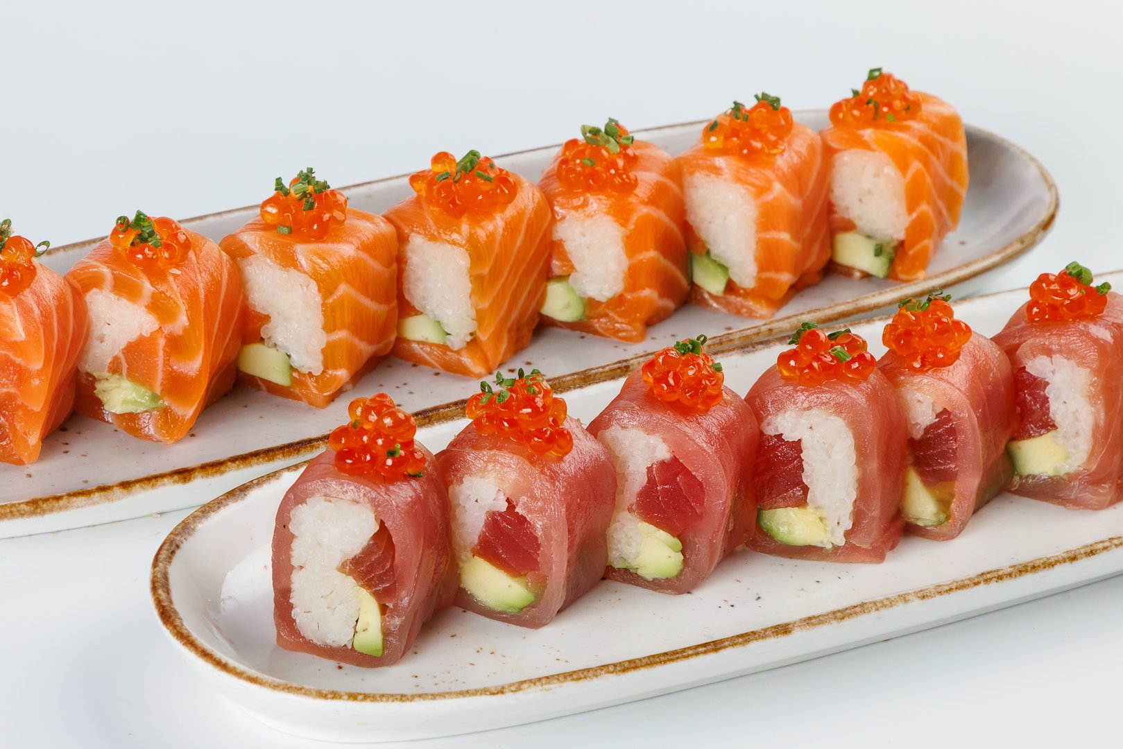 Ceramic tray with variety of salmon  end tuna sushi roll with avocado, appetizing japanese meal.