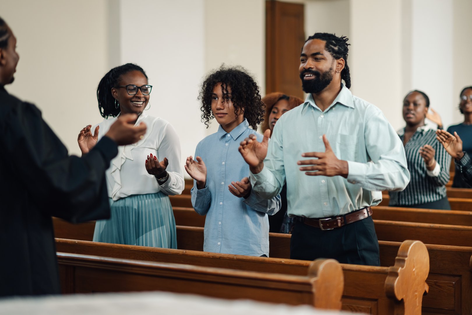 Diverse congregation claps and sings joyfully in a warm church, celebrating faith together. The choir leads in praise, creating community and spirituality