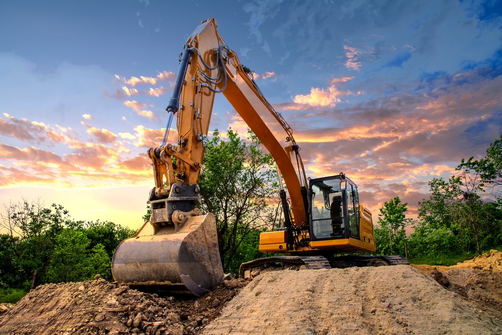 A stopping yellow excavator at an incredibly beautiful sunset