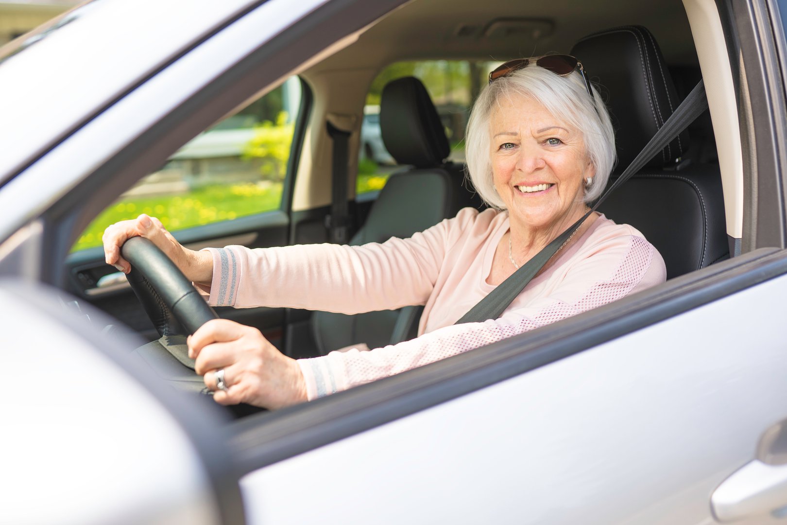A Happy and smiling senior woman in white car
